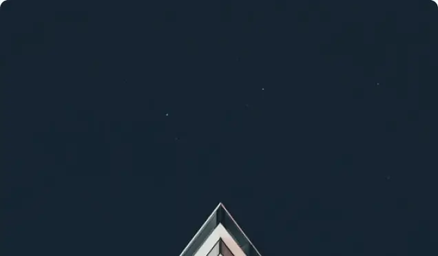 A triangular building peak against a dark night sky with faint stars.