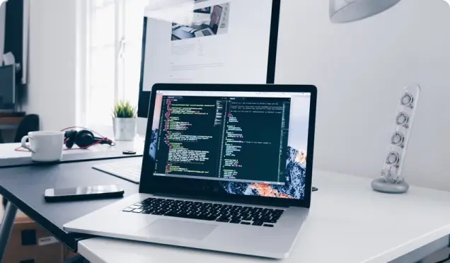  Laptop with code on screen on white desktop.