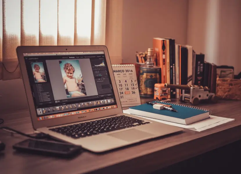 A laptop on a desk beside a framed photo of a woman, creating a personal workspace atmosphere.