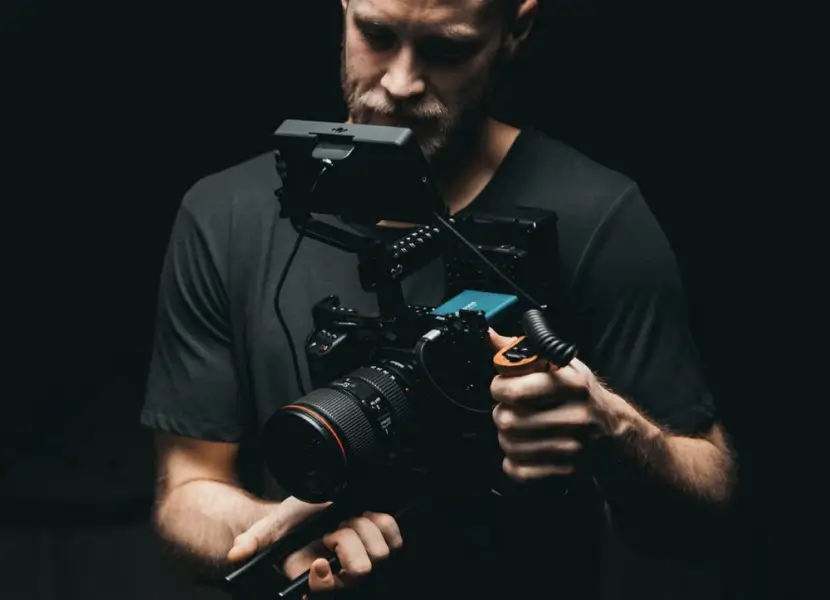 A man examines his camera closely, showcasing his interest in photography and attention to detail.