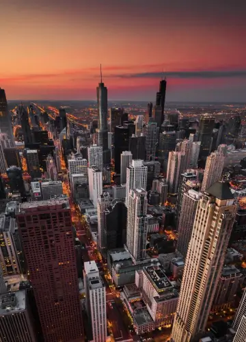 A stunning view of Chicago's skyline illuminated by the warm hues of sunset, casting reflections on the water below.